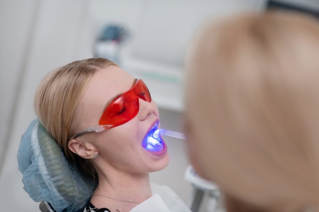 Dentist using ultraviolet lamp for patients tooth filling